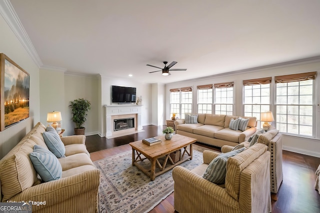 living area featuring baseboards, ornamental molding, ceiling fan, dark wood finished floors, and a fireplace with flush hearth