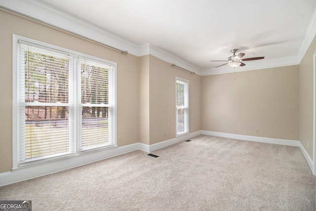 spare room with light colored carpet, ornamental molding, ceiling fan, and baseboards
