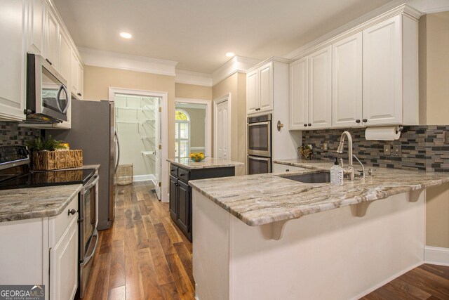 110 Kylemore Pass, Tyrone, GA 30290 - kitchen featuring stainless steel appliances, white cabinets, a sink, light stone counters, and crown molding