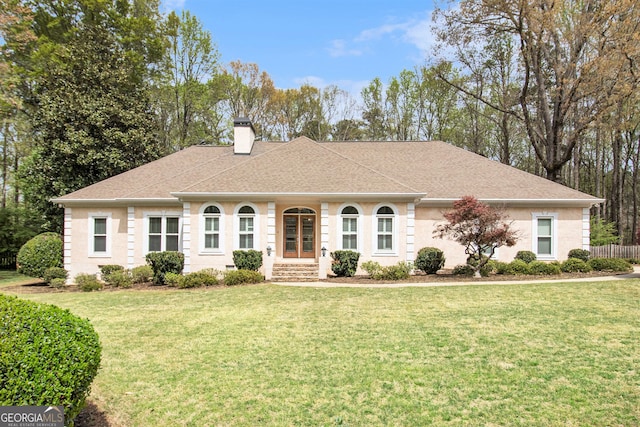 view of front of home featuring a chimney, a front yard, and roof with shingles