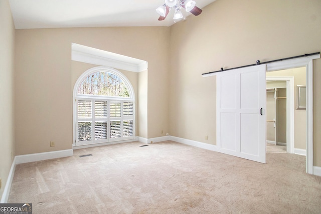 110 Kylemore Pass, Tyrone, GA 30290 - unfurnished bedroom featuring carpet floors, a barn door, high vaulted ceiling, a walk in closet, and a ceiling fan
