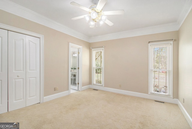 unfurnished bedroom with light carpet, ornamental molding, multiple windows, and baseboards