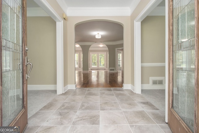 entrance foyer with arched walkways, crown molding, and french doors