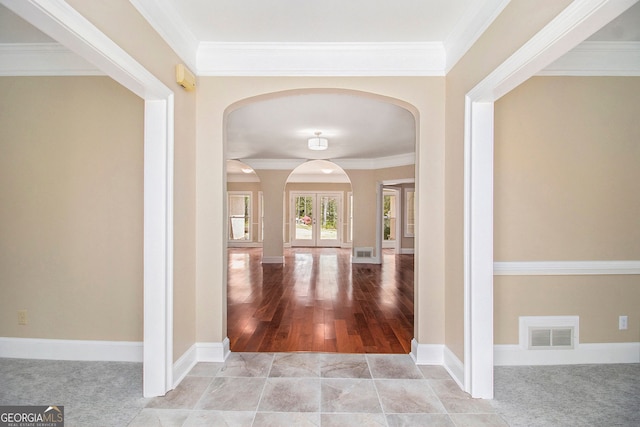 foyer featuring arched walkways, ornamental molding, and baseboards
