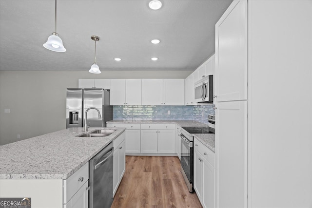 kitchen featuring white cabinets, light wood-style floors, appliances with stainless steel finishes, pendant lighting, and a sink