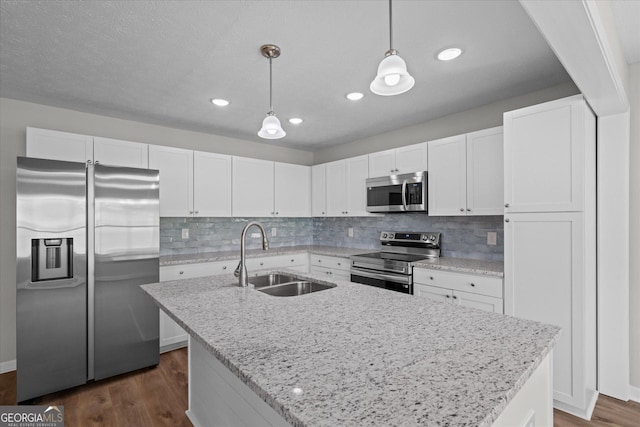 kitchen featuring backsplash, white cabinets, decorative light fixtures, appliances with stainless steel finishes, and a sink