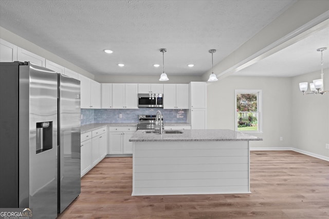 kitchen with tasteful backsplash, white cabinets, a sink, appliances with stainless steel finishes, and a kitchen island with sink