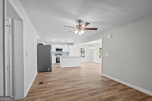 313 Ellenwood Dr, Bowdon, GA 30108 - unfurnished living room featuring a ceiling fan, a textured ceiling, light wood-style floors, a chandelier, and baseboards