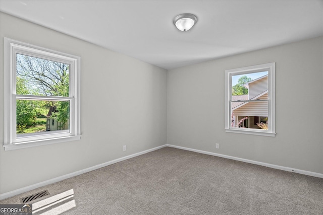 carpeted spare room with visible vents, baseboards, and a healthy amount of sunlight