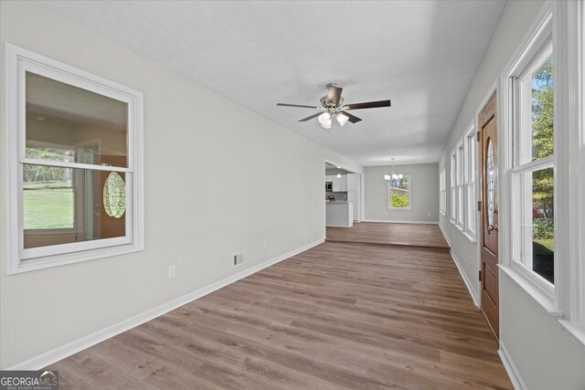 interior space featuring visible vents, baseboards, wood finished floors, and ceiling fan with notable chandelier