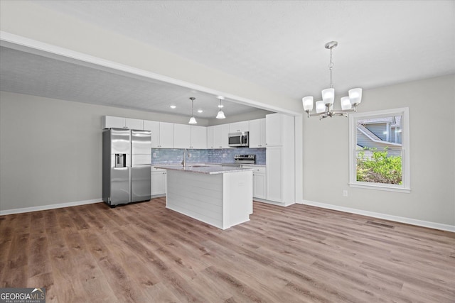 313 Ellenwood Dr, Bowdon, GA 30108 - kitchen featuring stainless steel appliances, a chandelier, backsplash, white cabinetry, and light wood-style floors