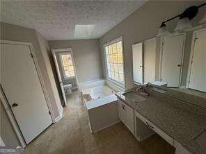 bathroom with a textured ceiling, a garden tub, and vanity