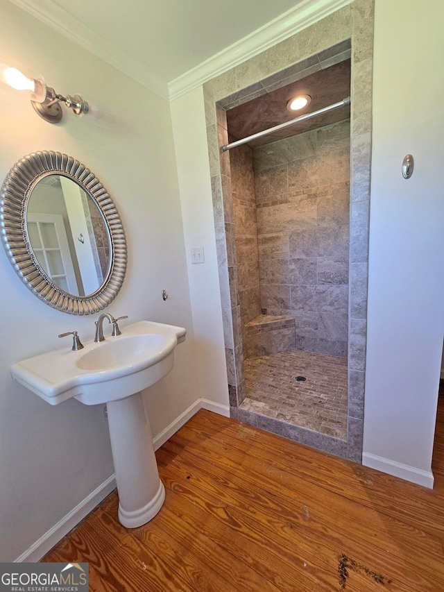 full bathroom with tiled shower, baseboards, ornamental molding, and wood finished floors