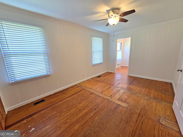unfurnished room featuring visible vents, baseboards, ceiling fan, crown molding, and hardwood / wood-style floors