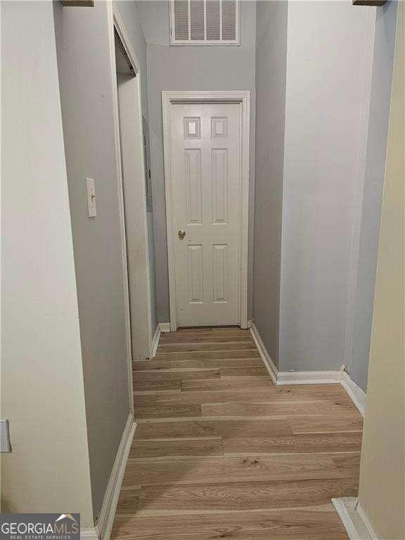 hallway with light wood-style floors, baseboards, and visible vents