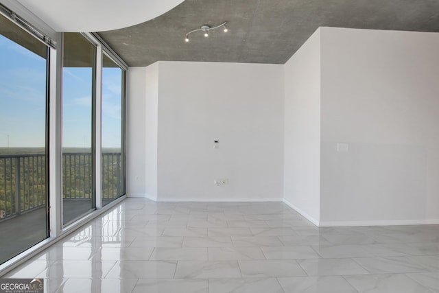 spare room with expansive windows and baseboards