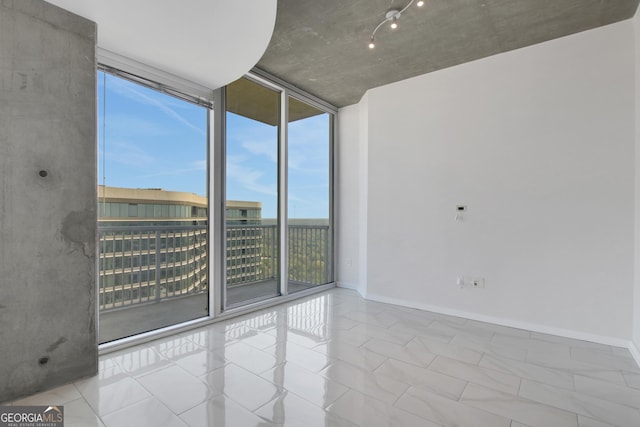 empty room with floor to ceiling windows and baseboards