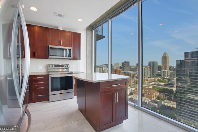 kitchen with visible vents, appliances with stainless steel finishes, a view of city, reddish brown cabinets, and decorative backsplash
