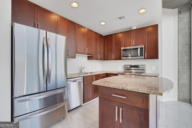 kitchen with visible vents, appliances with stainless steel finishes, light stone counters, a sink, and decorative backsplash