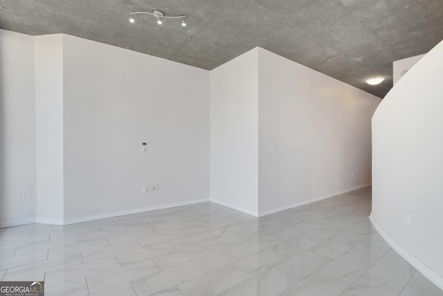 unfurnished room with marble finish floor and baseboards