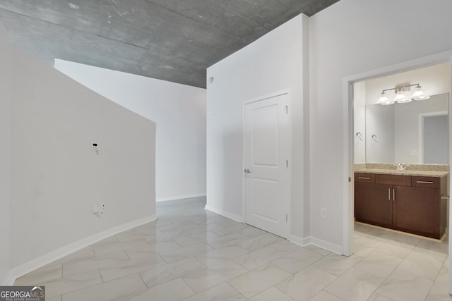 spare room with a sink, baseboards, and marble finish floor