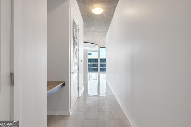 hall with floor to ceiling windows and baseboards