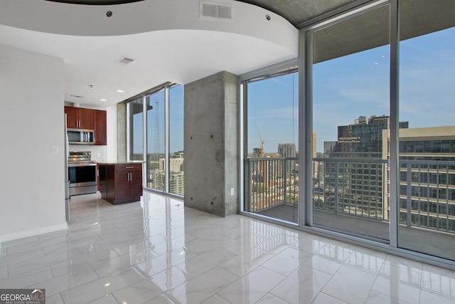 empty room with a view of city, visible vents, baseboards, and a wall of windows