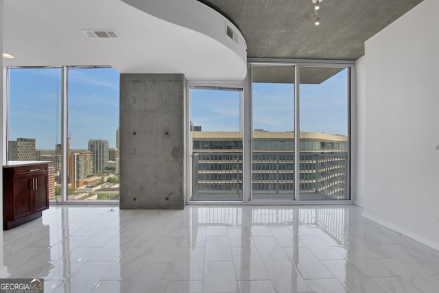 spare room with a view of city, visible vents, and a wall of windows