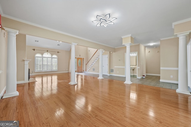 unfurnished living room featuring wood finished floors, baseboards, crown molding, and stairs