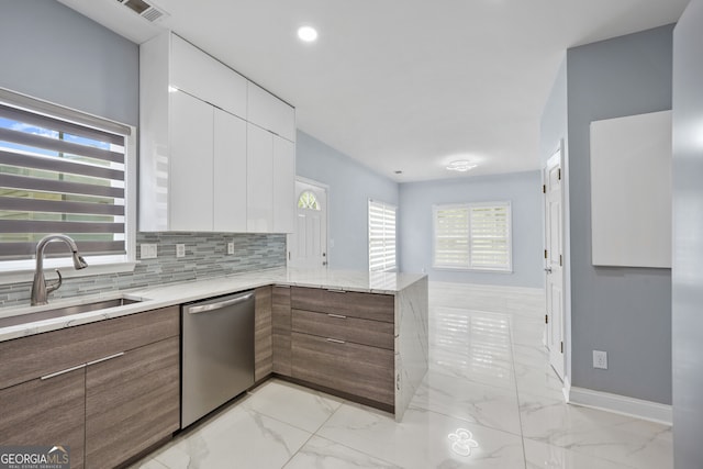 kitchen featuring stainless steel dishwasher, modern cabinets, a sink, light marble finish floors, and white cabinetry