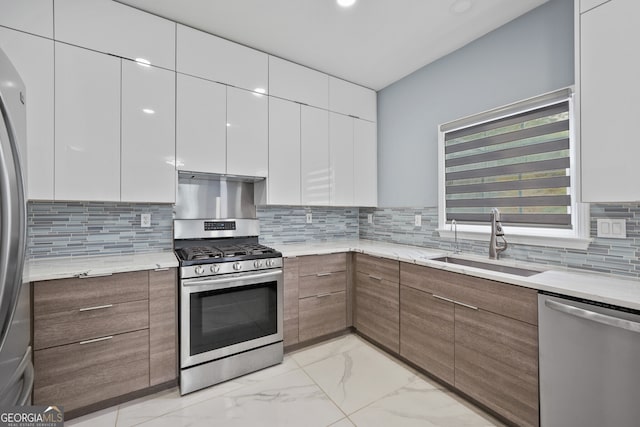 kitchen with appliances with stainless steel finishes, a sink, modern cabinets, and light marble finish floors