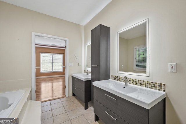 full bath with two vanities, tile patterned floors, a bath, and decorative backsplash