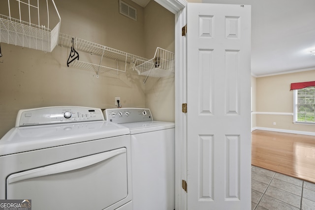 laundry room with independent washer and dryer, light tile patterned flooring, and baseboards