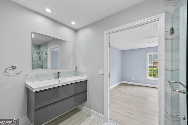 bathroom with a shower stall, baseboards, wood finished floors, vanity, and recessed lighting