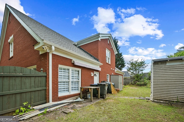 view of home's exterior with roof with shingles, brick siding, a shed, and an outdoor structure
