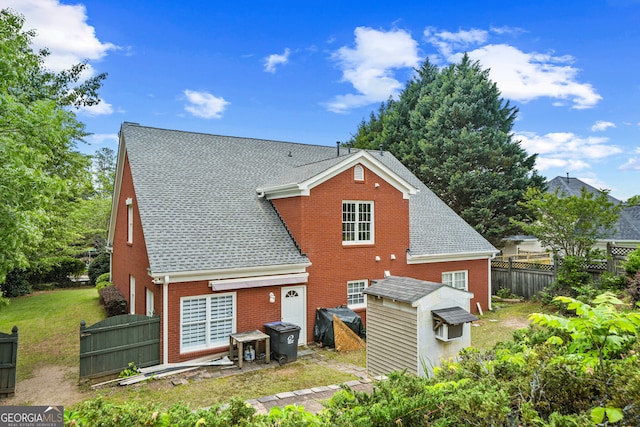 back of property featuring brick siding, fence, and roof with shingles