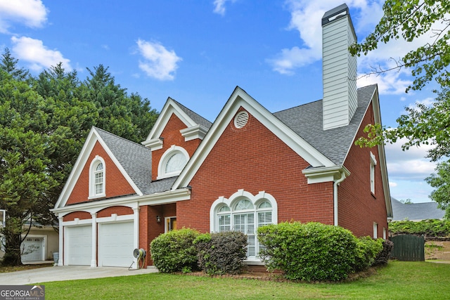 traditional-style house with roof with shingles, brick siding, a chimney, and a front yard