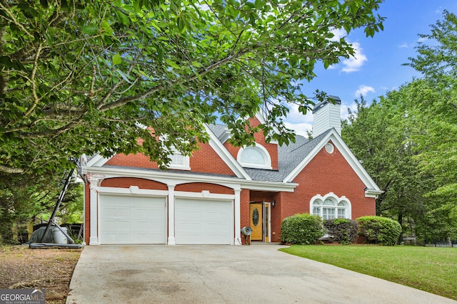 view of front facade featuring brick siding, concrete driveway, a chimney, a front lawn, and roof with shingles