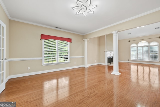 unfurnished living room featuring ornate columns, a fireplace, plenty of natural light, wood finished floors, and ornamental molding