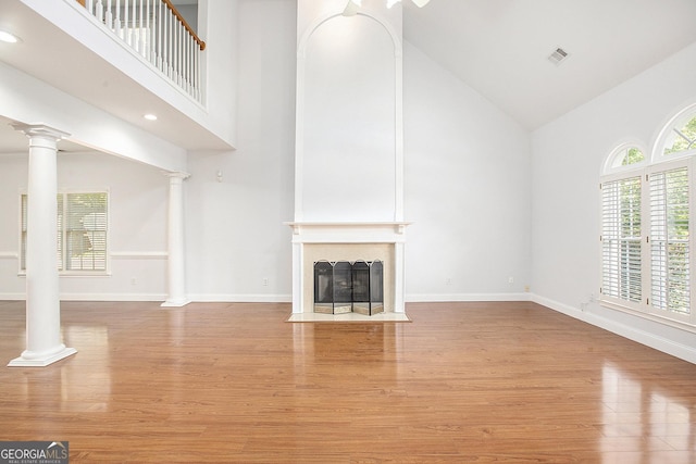 4505 Lakefield Bnd, Berkeley Lake, GA 30096 - unfurnished living room featuring high vaulted ceiling, ornate columns, wood finished floors, a fireplace with flush hearth, and recessed lighting