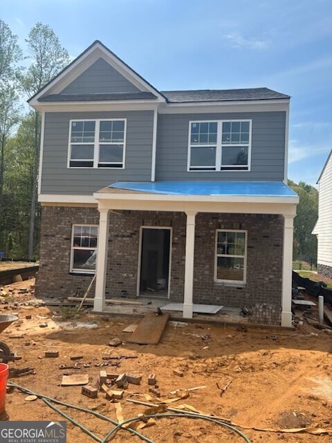 rear view of house with a porch and brick siding