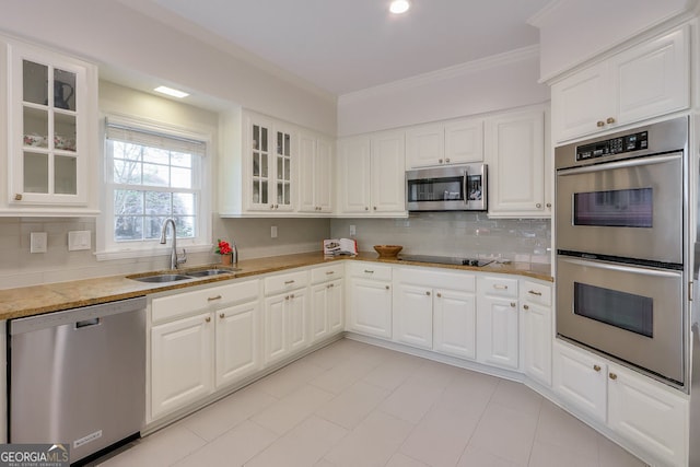 kitchen featuring appliances with stainless steel finishes, a sink, crown molding, decorative backsplash, and glass insert cabinets