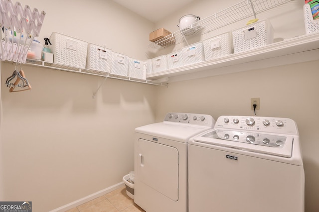 laundry area featuring washer and dryer, light tile patterned floors, and baseboards