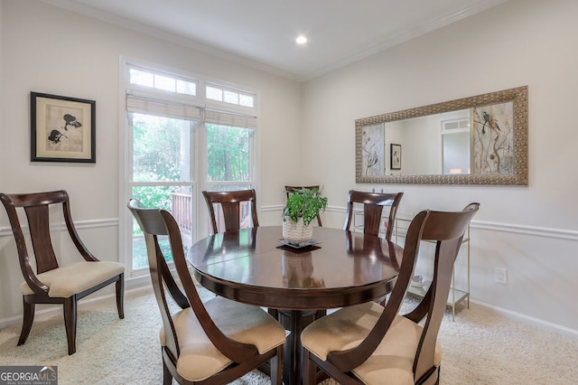 carpeted dining room with crown molding and baseboards