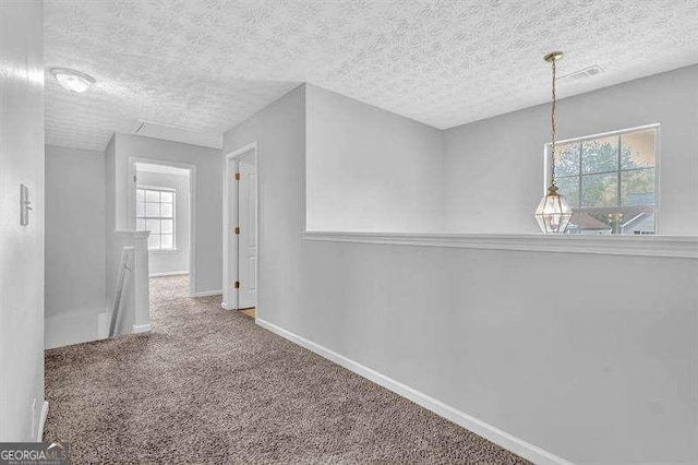 corridor featuring a textured ceiling, baseboards, an upstairs landing, and carpet floors