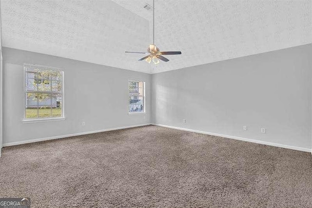 carpeted empty room with ceiling fan, lofted ceiling, baseboards, and a textured ceiling