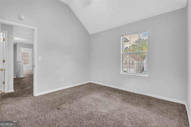 unfurnished bedroom featuring multiple windows, carpet flooring, vaulted ceiling, and a textured ceiling