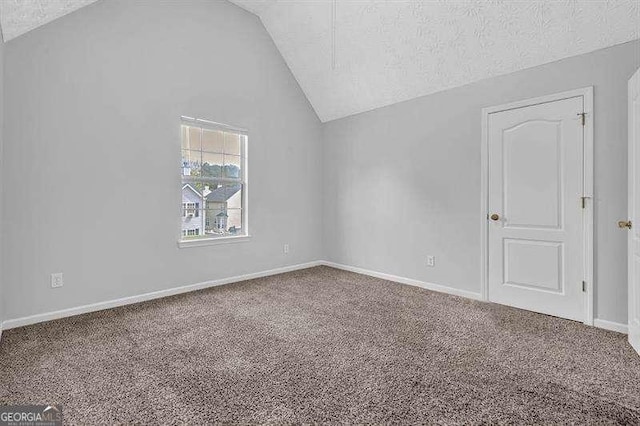 interior space featuring lofted ceiling, baseboards, a textured ceiling, and carpet floors