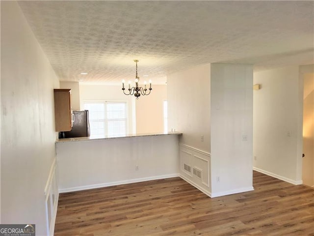 unfurnished dining area with an inviting chandelier and wood finished floors