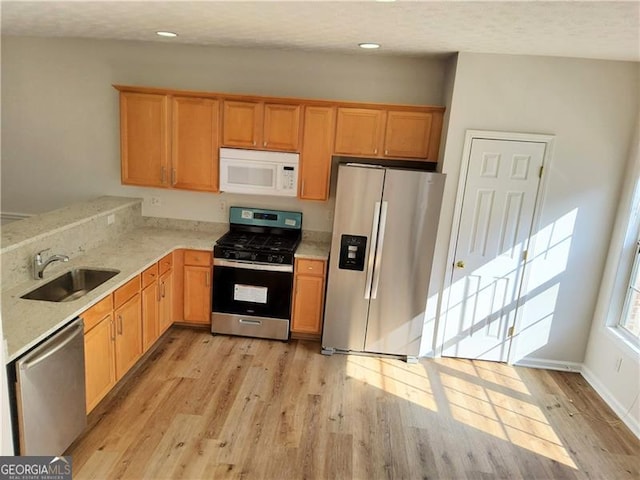 kitchen featuring recessed lighting, light wood-style floors, stainless steel appliances, and a sink